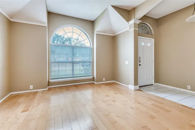 an empty room with wooden floor cabinet and windows
