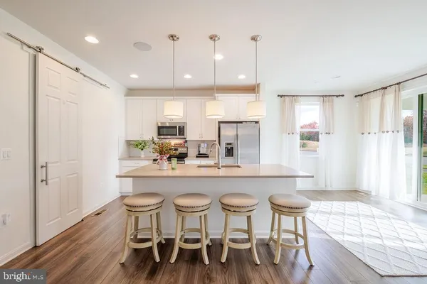 a kitchen with stainless steel appliances granite countertop a dining table chairs and white cabinets
