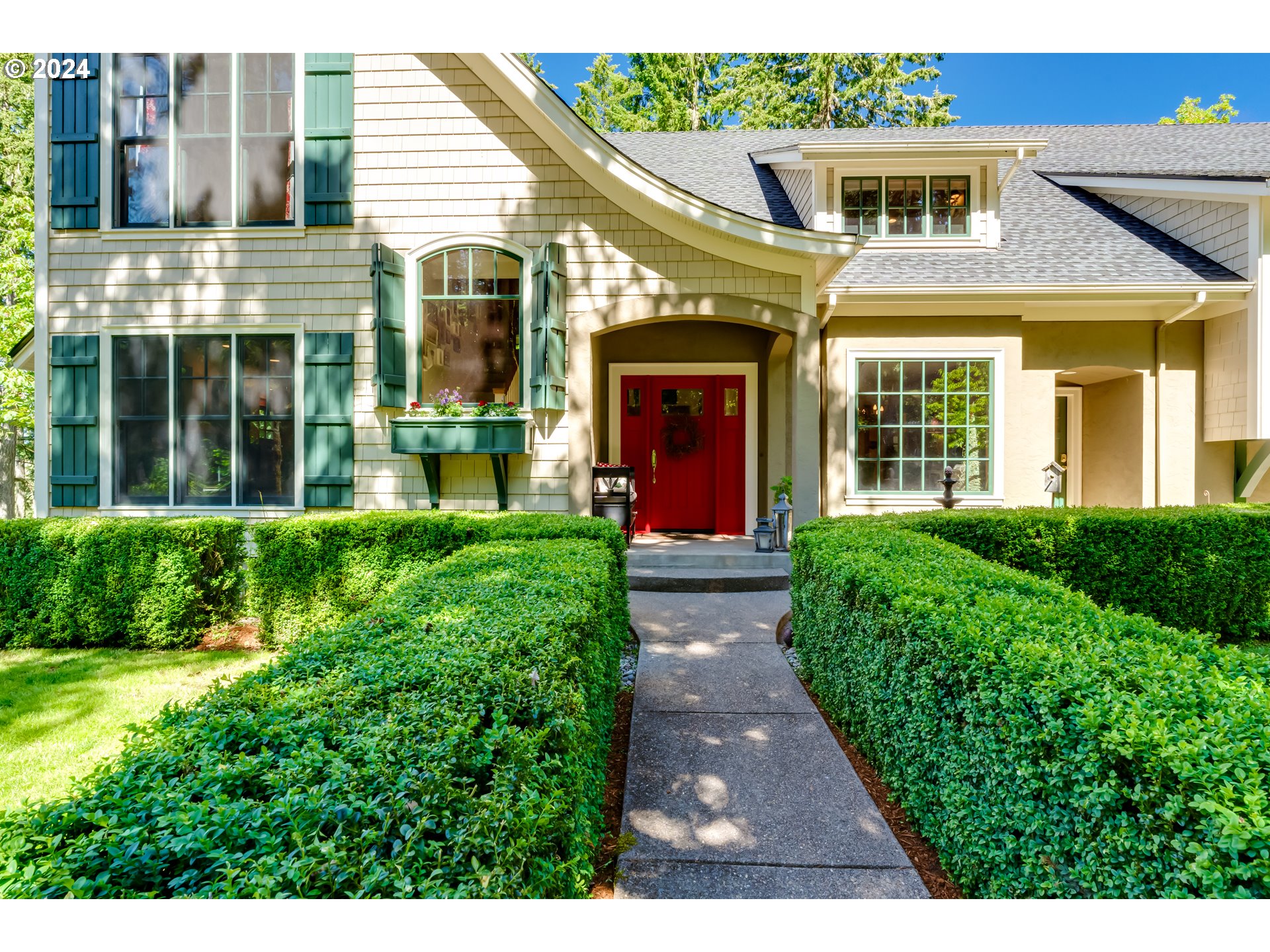 a view of a brick house with a large windows plants and large trees