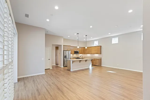 a large kitchen with stainless steel appliances a large counter top a sink a refrigerator and a stove