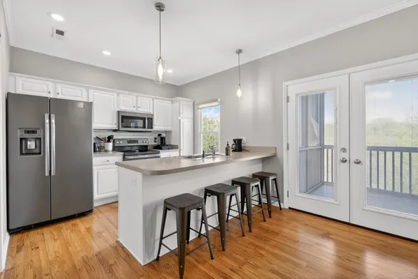 a kitchen with stainless steel appliances granite countertop a refrigerator a sink dishwasher a stove and white cabinets with wooden floor