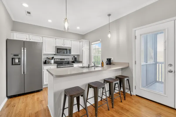 a kitchen with stainless steel appliances granite countertop a refrigerator a sink dishwasher a stove and a refrigerator with wooden floor