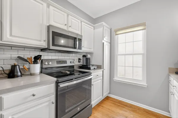 a kitchen with white cabinets and appliances