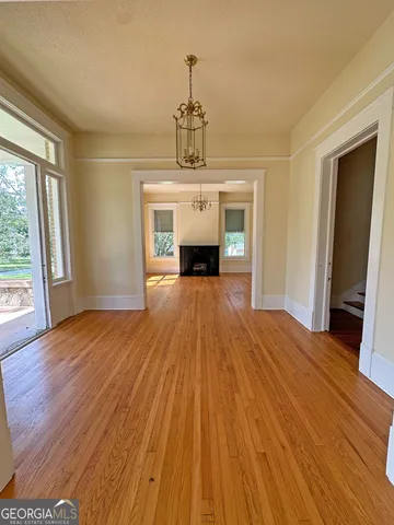 a view of a room with wooden floor fireplace and window