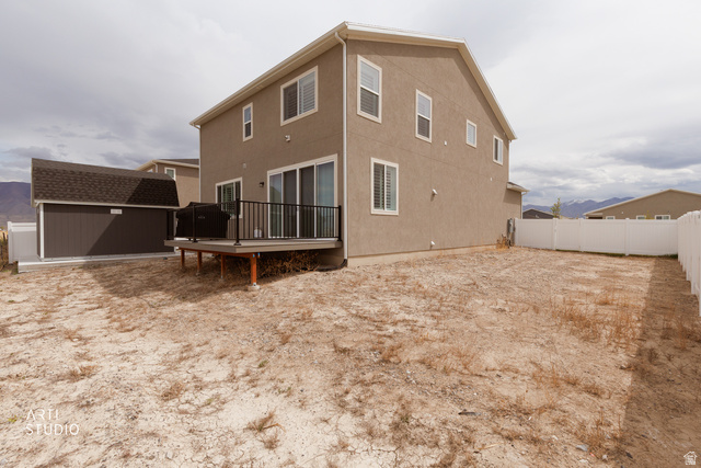 540 Lefty Lane Tooele, UT 84074 - Photo 33 of 48 Back of property with a deck, a storage unit, a fenced backyard, and stucco siding
