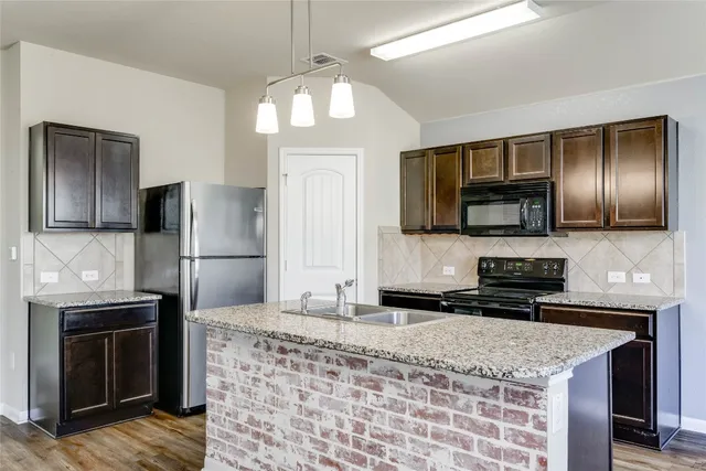 a kitchen with stainless steel appliances granite countertop a refrigerator a stove a sink and a microwave