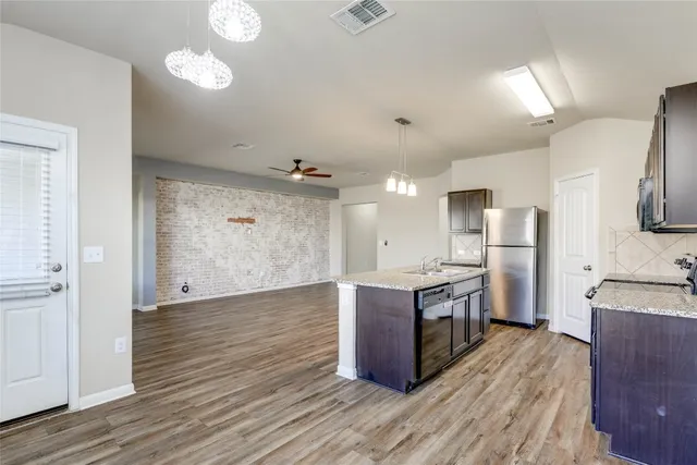 a large kitchen with stainless steel appliances granite countertop a large stove a sink dishwasher and a refrigerator with wooden floor