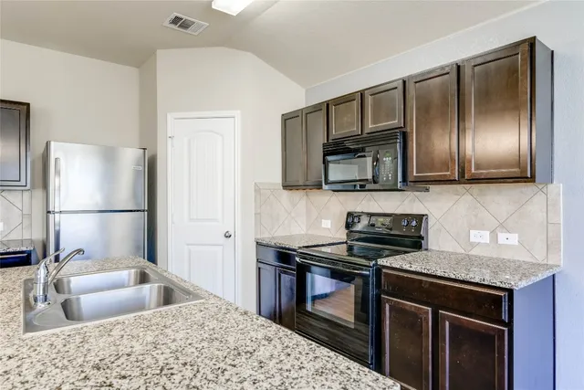a kitchen with stainless steel appliances granite countertop a sink stove and refrigerator