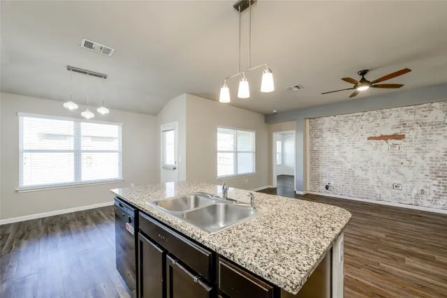 a kitchen with granite countertop a sink cabinets and wooden floor