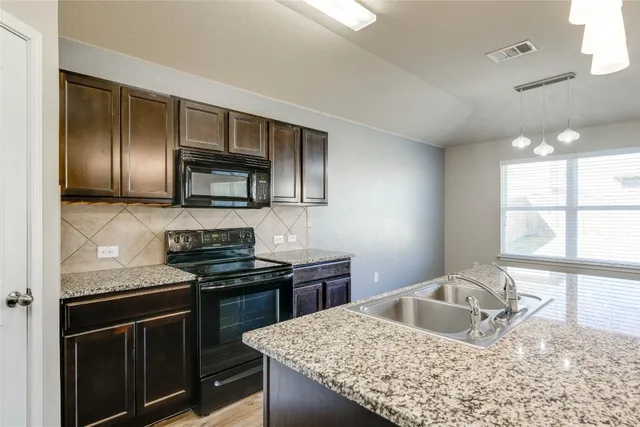 a kitchen with granite countertop stainless steel appliances sink stove microwave and cabinets