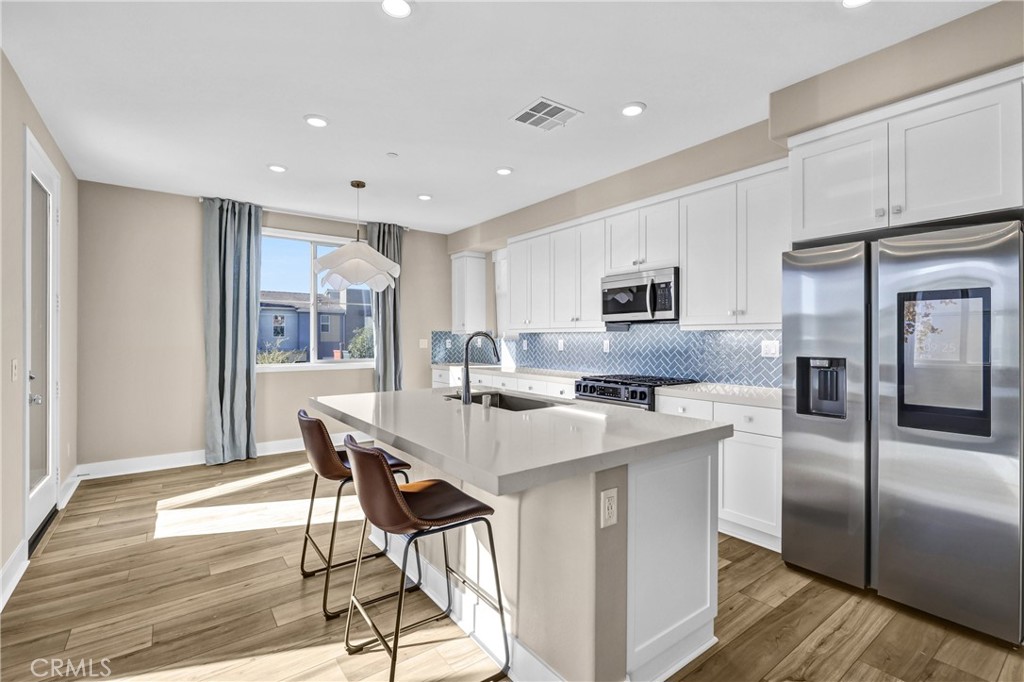 31861 Williams Way Rancho Mission Viejo, CA 92694 - Photo 6 of 28 a kitchen with stainless steel appliances granite countertop a sink a stove a refrigerator with a dining table and chairs