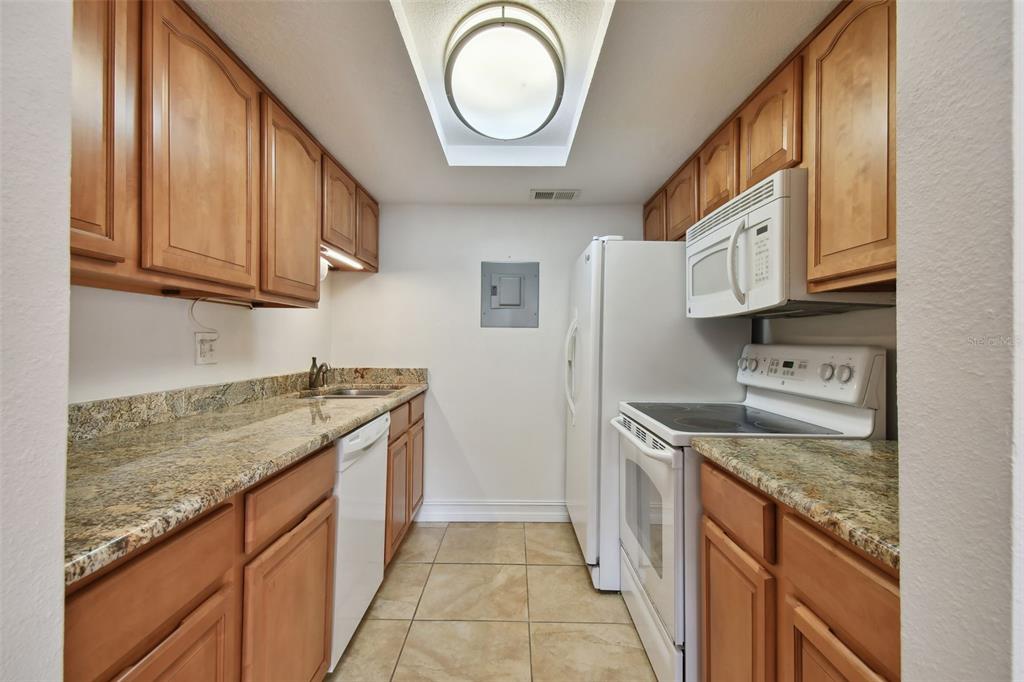8931 Blind Pass Road, Unit 257 St. Pete Beach, FL 33706 - Photo 5 of 10 a kitchen with granite countertop stainless steel appliances a stove a sink and a microwave