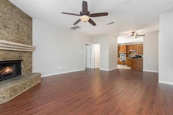 a view of empty room with wooden floor fireplace and a window