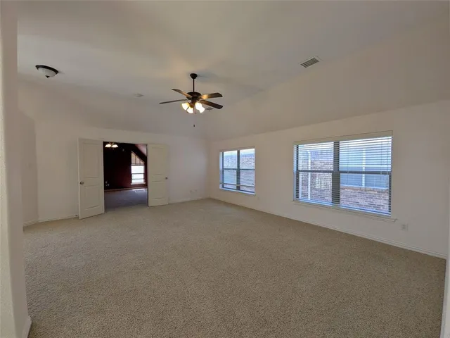 a view of an empty room with chandelier and fan