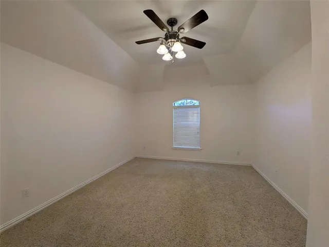 an empty room with a chandelier fan and windows