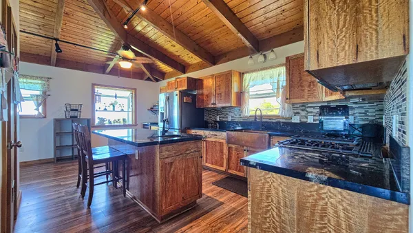 a kitchen with stainless steel appliances granite countertop a stove a sink dishwasher a dining table and chairs with wooden floor