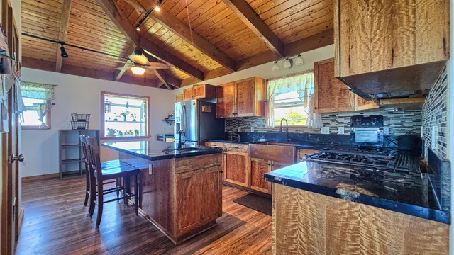 a kitchen with stainless steel appliances granite countertop a stove a sink dishwasher a dining table and chairs with wooden floor