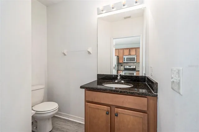 a bathroom with a granite countertop sink toilet and mirror