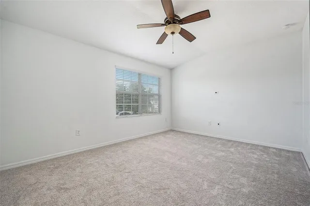 an empty room with a window and a fan