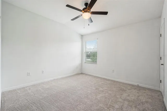an empty room with a window and a fan