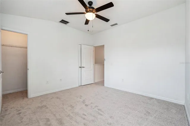 an empty room with a ceiling fan and a window