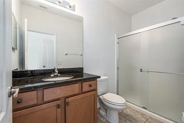 a bathroom with a granite countertop sink toilet and a mirror