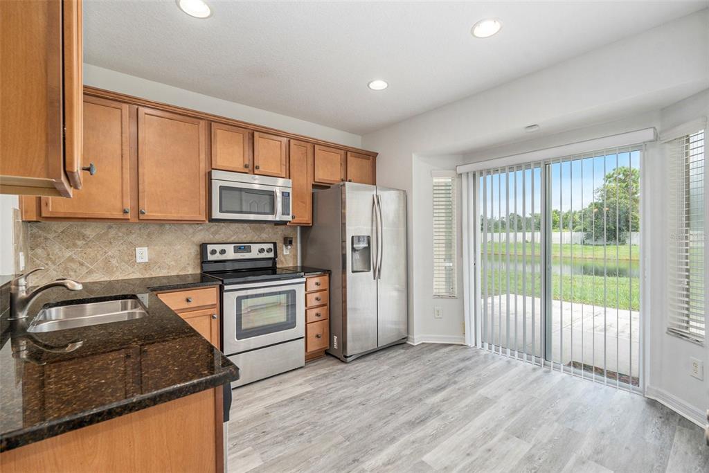 15854 Stable Run Drive Spring Hill, FL 34610 - Photo 8 of 28 a kitchen with stainless steel appliances granite countertop a refrigerator stove sink and cabinets
