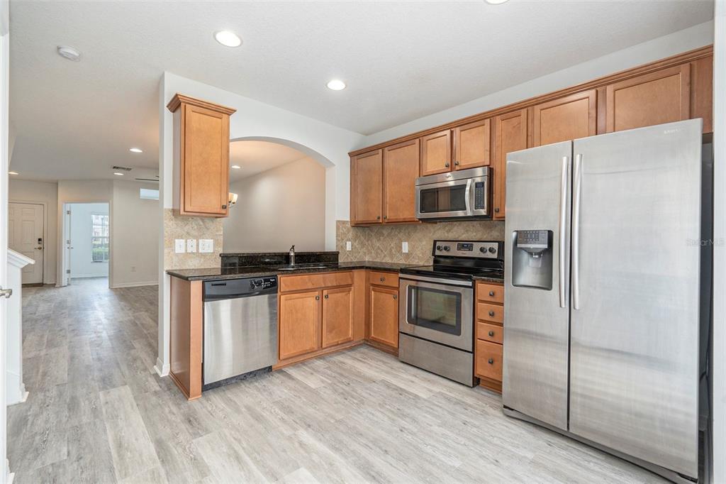 15854 Stable Run Drive Spring Hill, FL 34610 - Photo 10 of 28 a kitchen with granite countertop a refrigerator stove top oven and sink