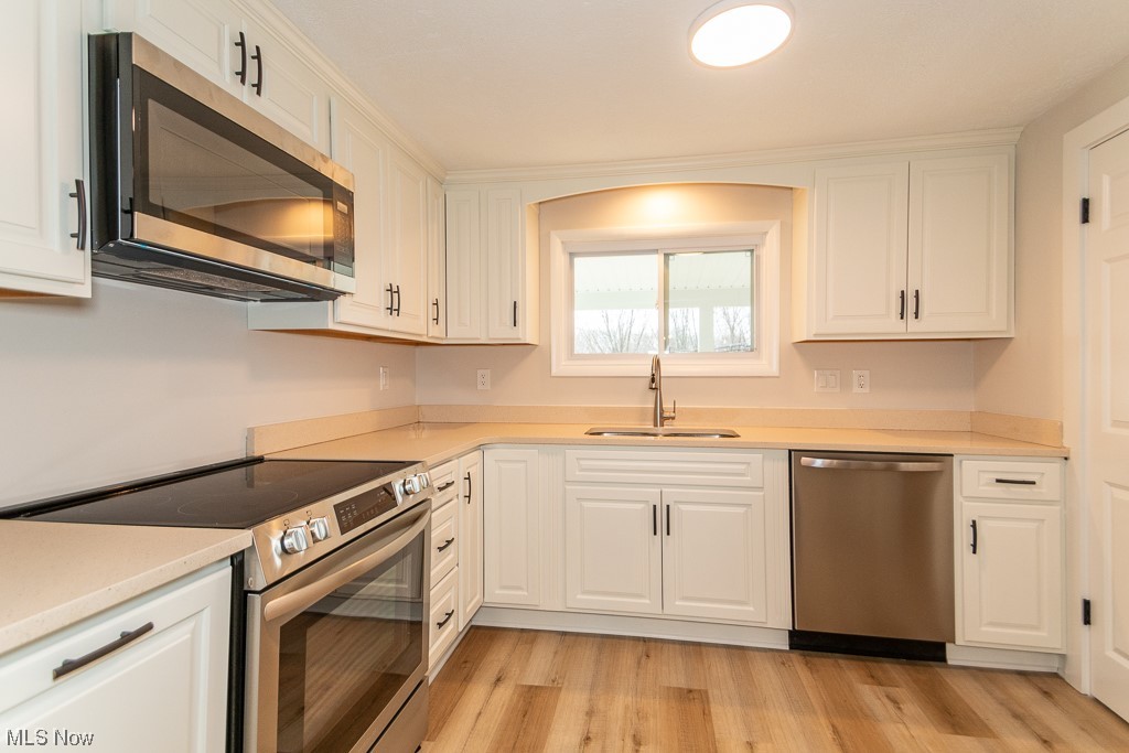 9490 Hoose Road Mentor, OH 44060 - Photo 4 of 27 Kitchen with white cabinets, light hardwood / wood-style flooring, sink, and stainless steel appliances