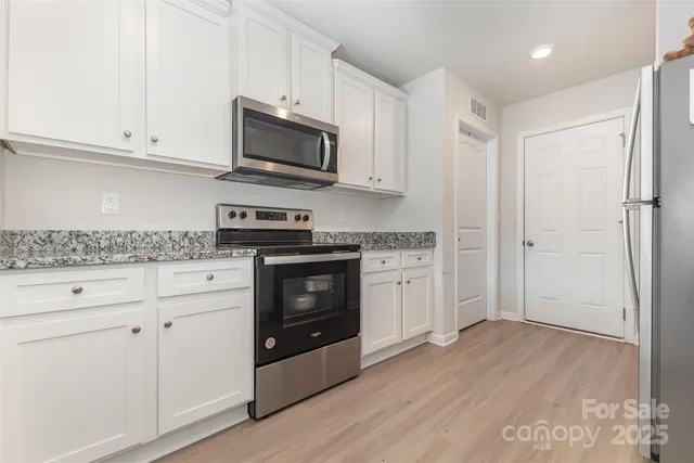 a kitchen with granite countertop white cabinets and stainless steel appliances