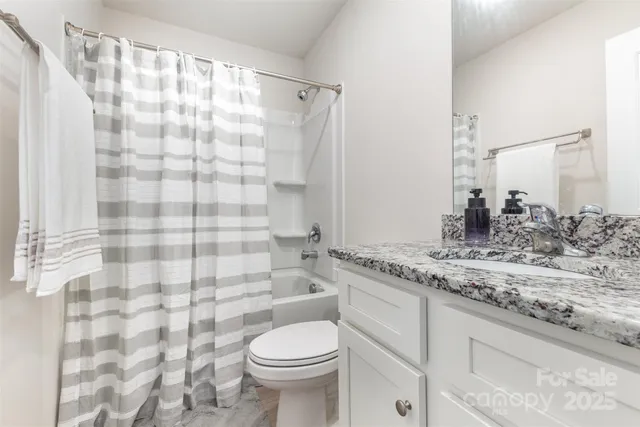 a bathroom with a granite countertop sink a toilet and shower