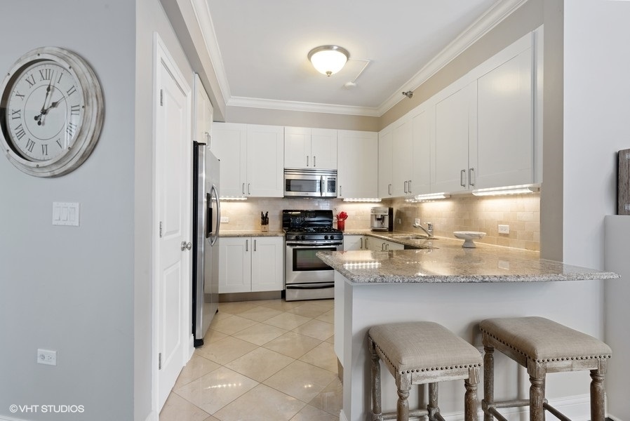 744 North Clark Street, Unit 501 Chicago, IL 60654 - Photo 5 of 16 a kitchen with stainless steel appliances granite countertop a refrigerator and a stove top oven