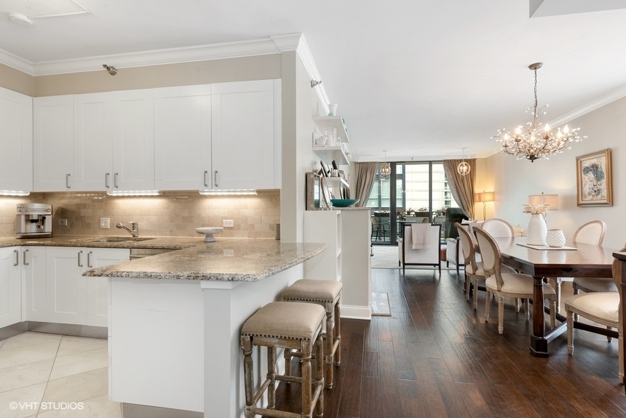 744 North Clark Street, Unit 501 Chicago, IL 60654 - Photo 8 of 16 a kitchen with stainless steel appliances granite countertop a stove top oven a dining table and chairs with wooden floor