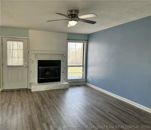 an empty room with wooden floor fireplace cabinet and windows