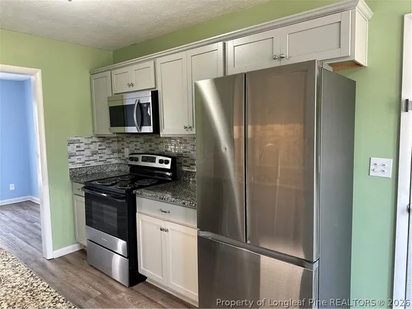 a kitchen with stainless steel appliances granite countertop a refrigerator and a stove top oven