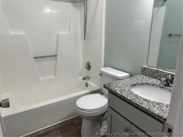 a bathroom with a granite countertop toilet a sink and a bathtub