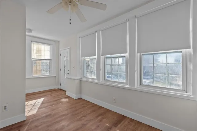 a view of an empty room with a window and wooden floor