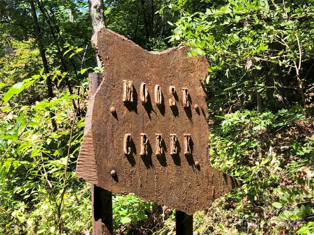 a sign that is sitting in front of a tree