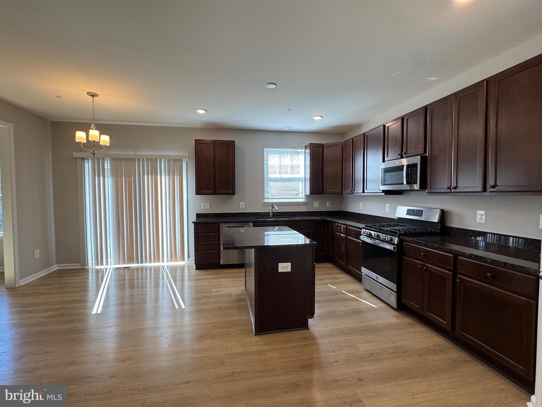 101 Albemarle Court Cambridge, MD 21613 - Photo 17 of 47 a kitchen with stainless steel appliances granite countertop wooden cabinets a stove a sink and a wooden floor