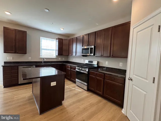 a kitchen with kitchen island granite countertop a sink cabinets and stainless steel appliances
