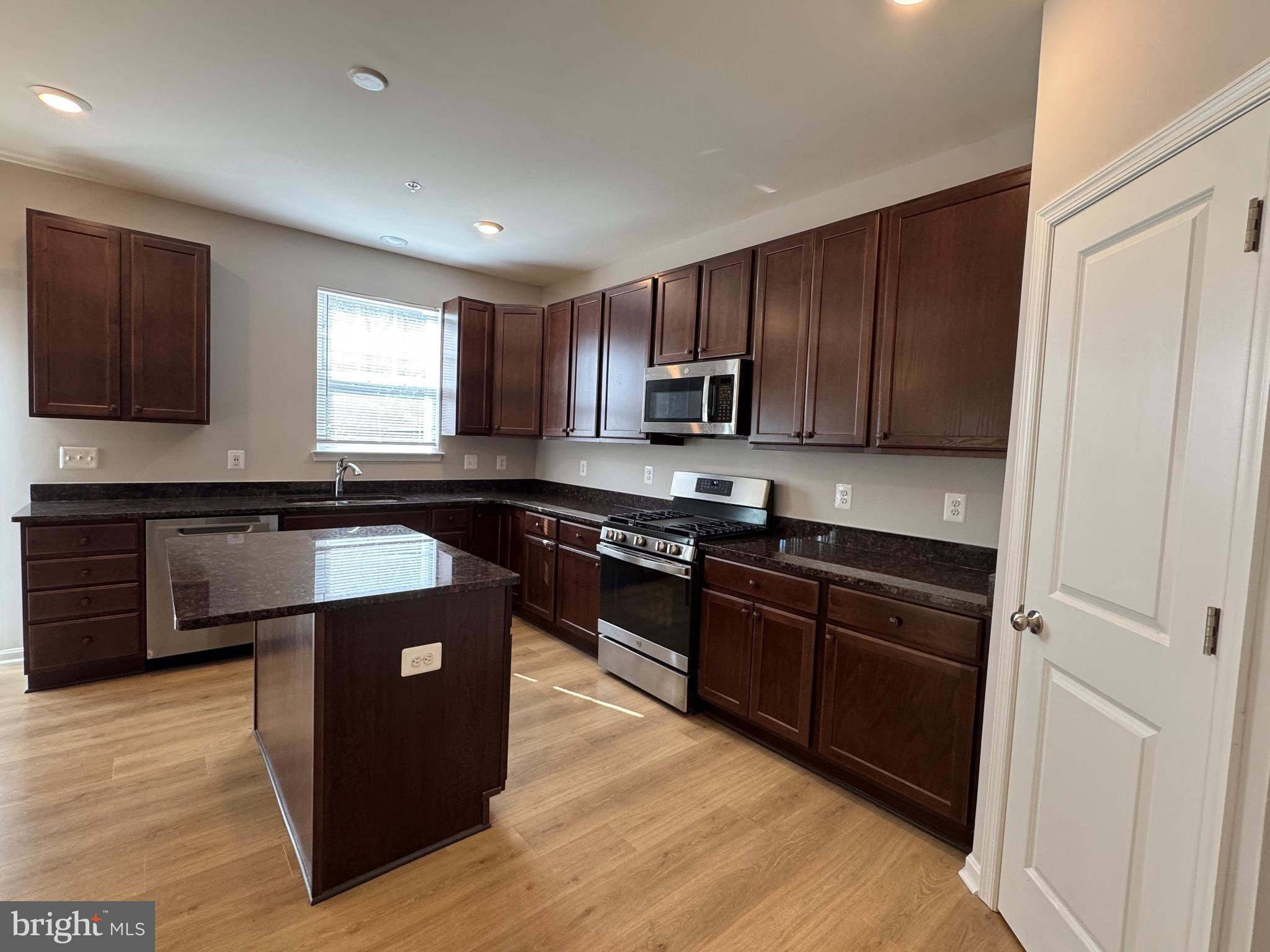 101 Albemarle Court Cambridge, MD 21613 - Photo 18 of 47 a kitchen with kitchen island granite countertop a sink cabinets and stainless steel appliances