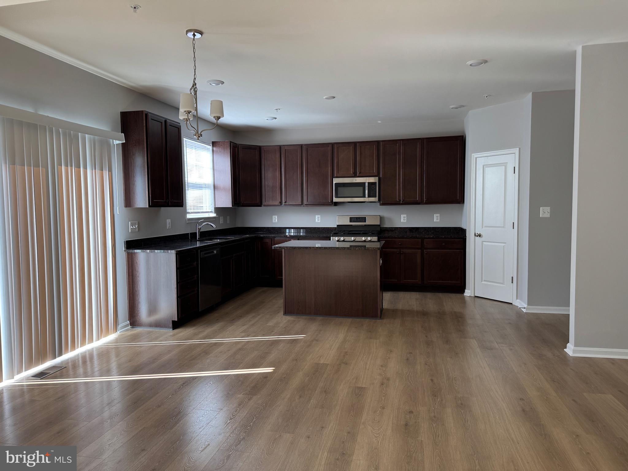 101 Albemarle Court Cambridge, MD 21613 - Photo 20 of 47 a kitchen with stainless steel appliances granite countertop a sink a stove top oven and wooden floors
