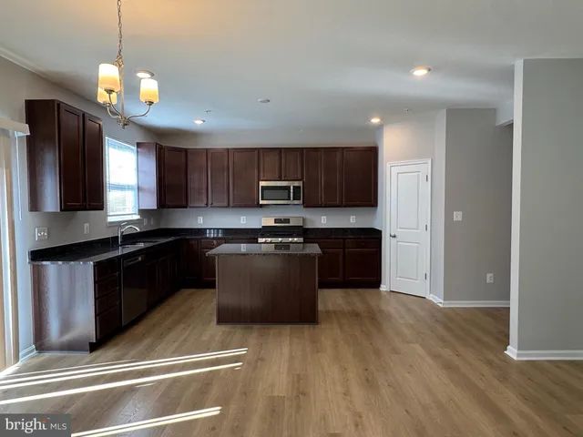 a kitchen with stainless steel appliances granite countertop wooden cabinets a refrigerator a stove a sink and a microwave