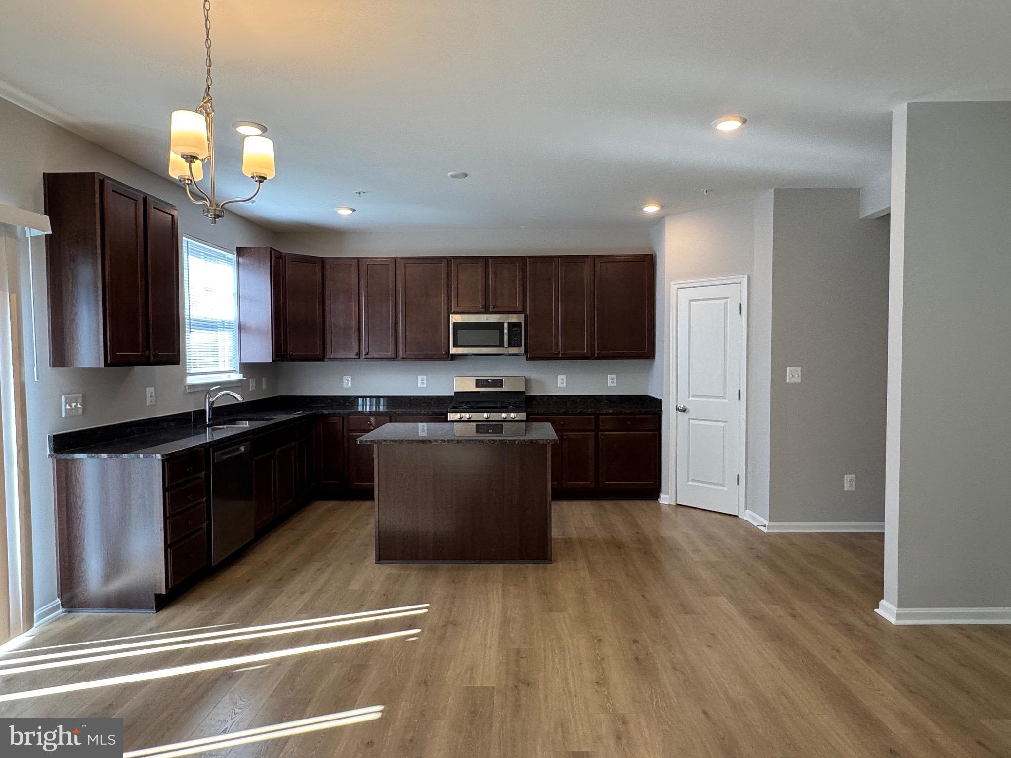101 Albemarle Court Cambridge, MD 21613 - Photo 10 of 47 a kitchen with stainless steel appliances granite countertop wooden cabinets a refrigerator a stove a sink and a microwave