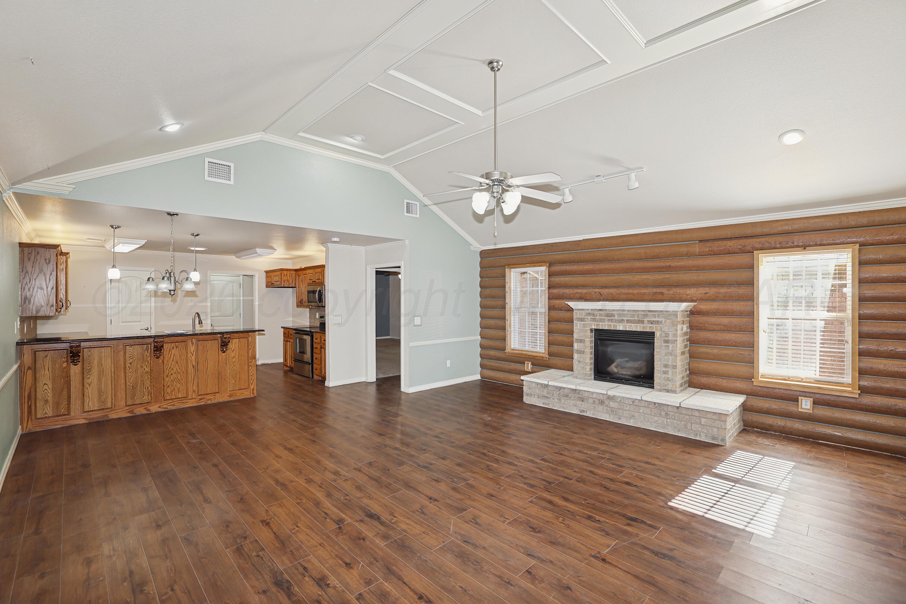 6709 Mosley Street Amarillo, TX 79119 - Photo 5 of 29 an empty room with wooden floor fireplace and windows