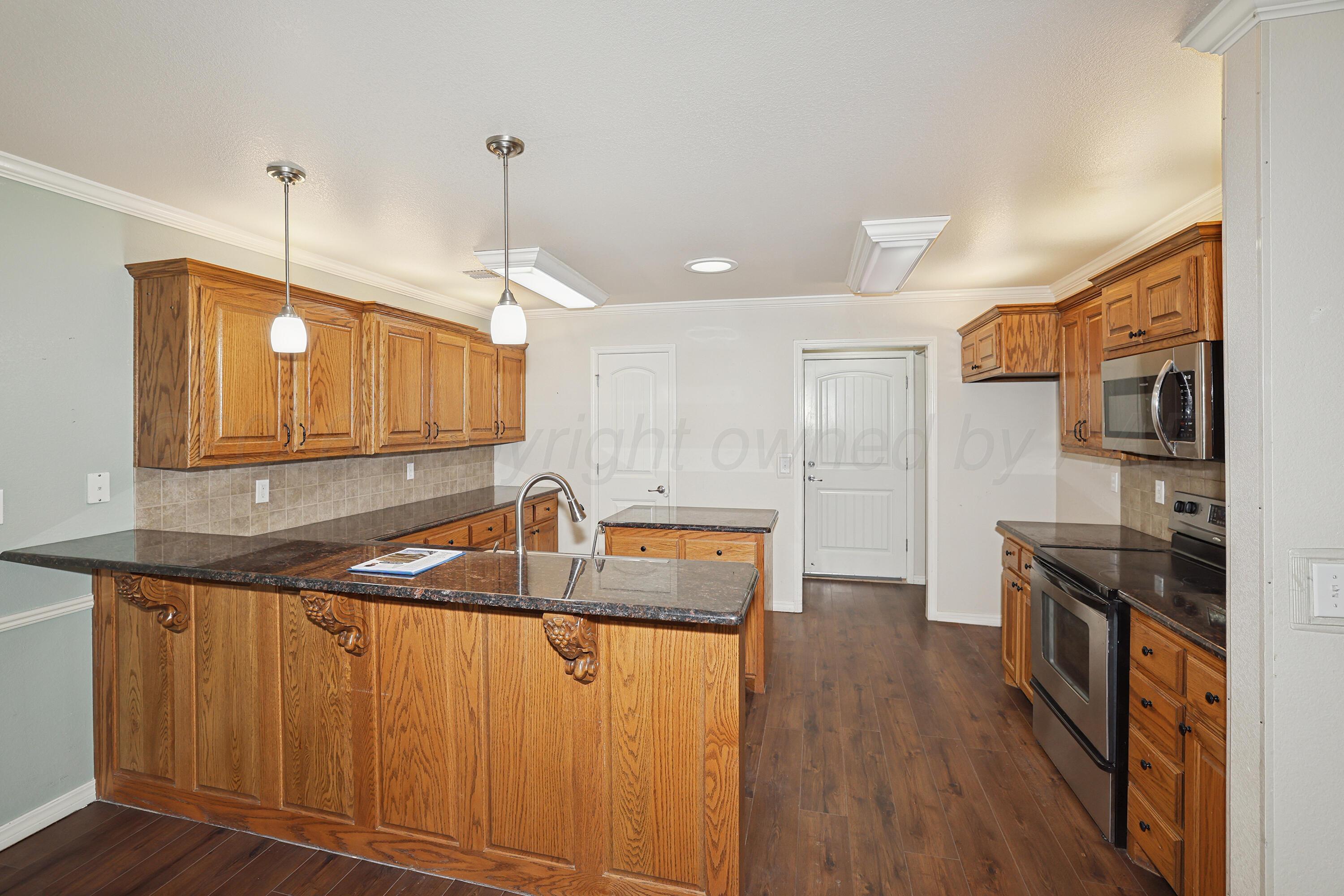 6709 Mosley Street Amarillo, TX 79119 - Photo 8 of 29 a kitchen with stainless steel appliances granite countertop a sink a stove and a wooden floors