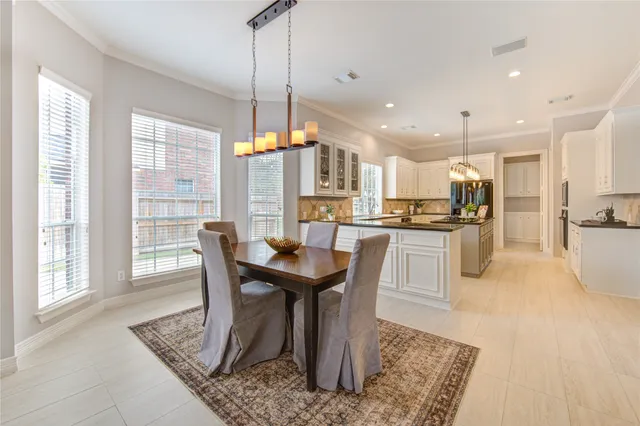 a kitchen with stainless steel appliances granite countertop a table chairs and a refrigerator