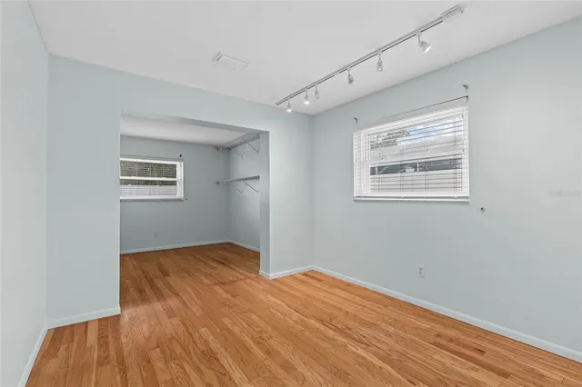 a view of an empty room with wooden floor and a window