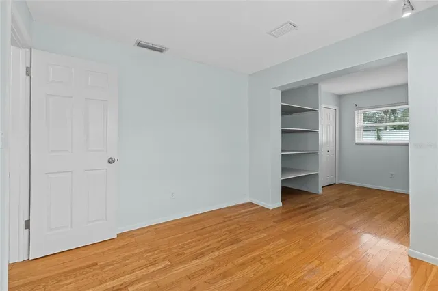 a view of empty room with wooden floor and window