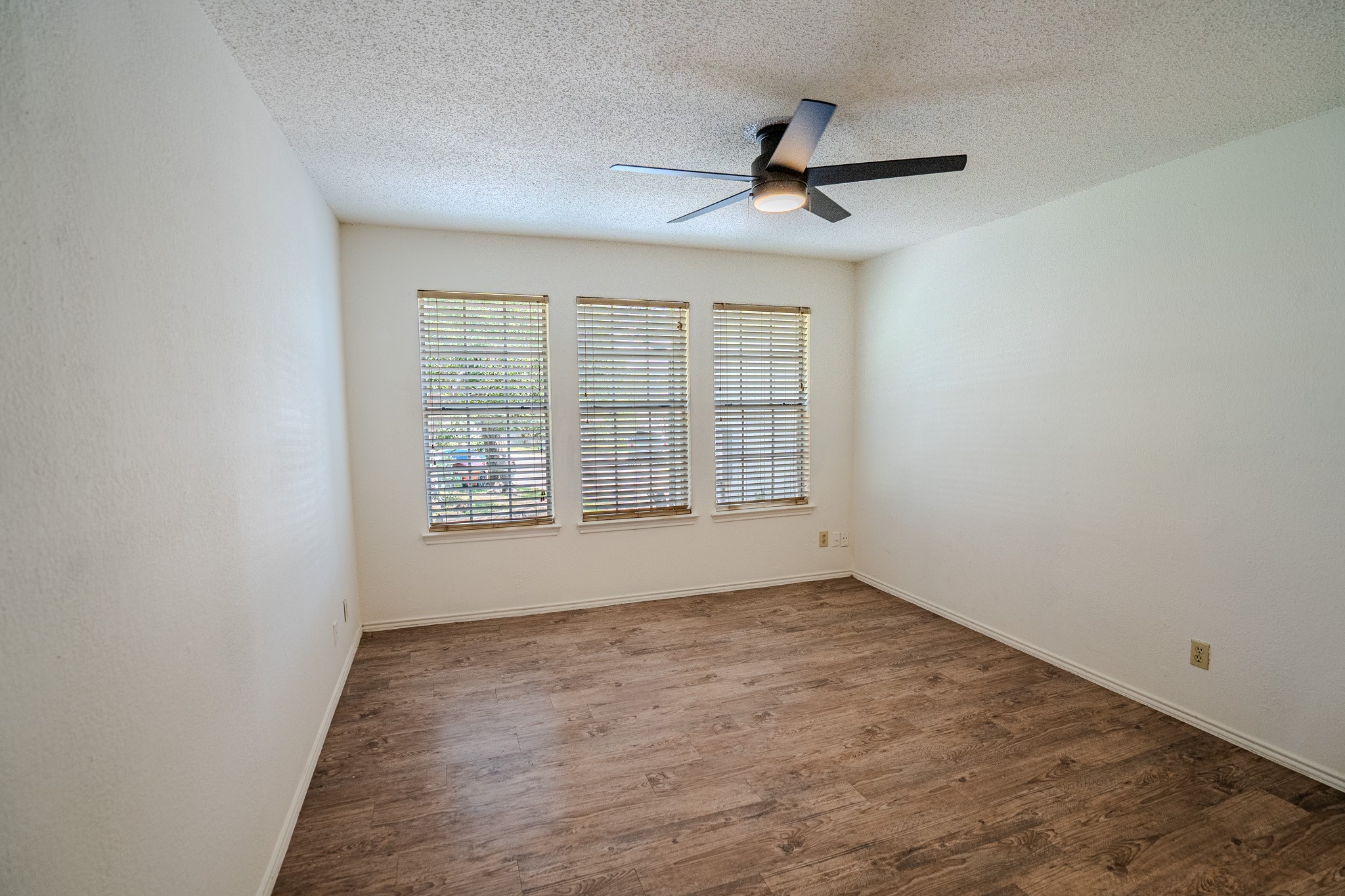 517 Cutty Trail, Unit B Lakeway, TX 78734 - Photo 11 of 16 A well-lit bedroom features three windows, wood flooring, and a ceiling fan for comfort.